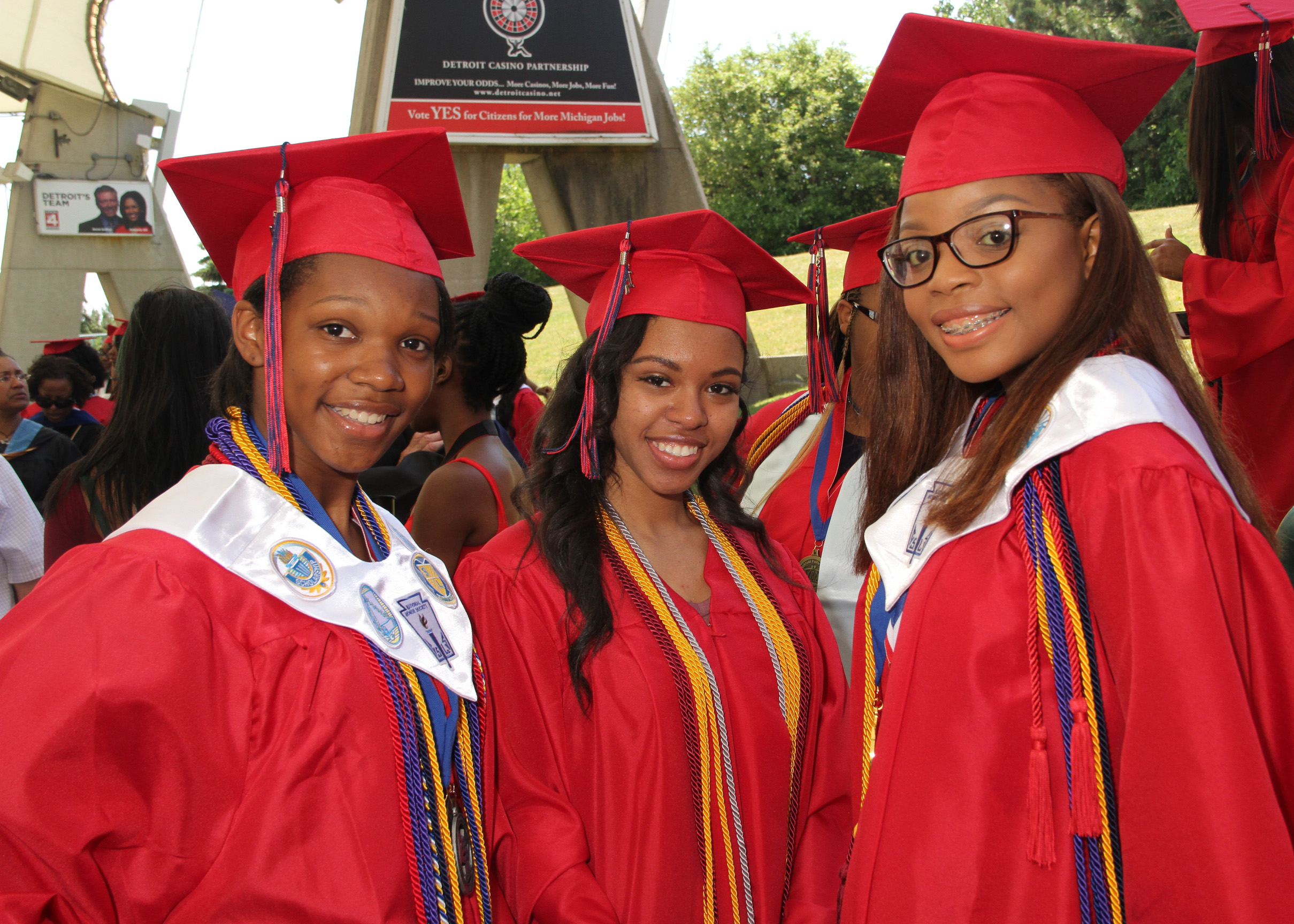 Three young ladies in red graduation robes.