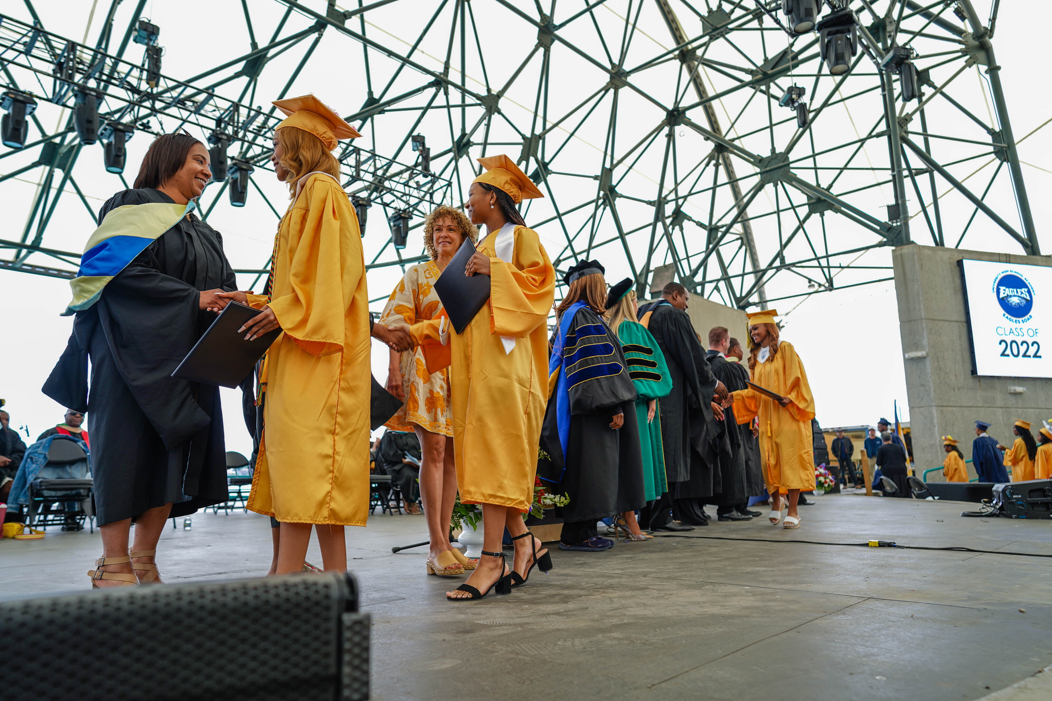 U 2022 Graduation--Graduates shaking hands across stage.